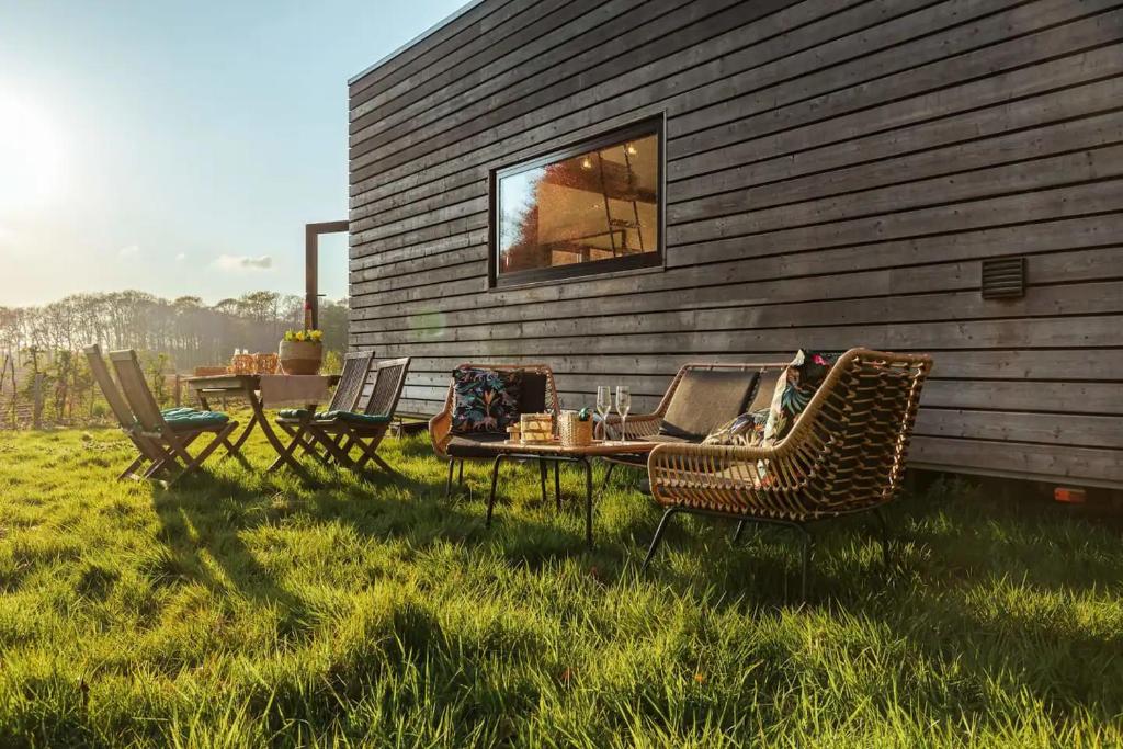 a table and chairs on the grass next to a building at Tiny House Natuur & cultuur nabij Brugge! in Beernem