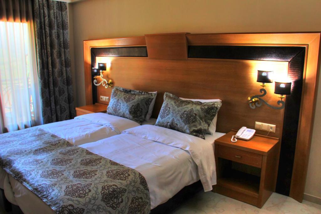 a bedroom with a large bed with a wooden headboard at Grand Meteora Hotel in Kalabaka