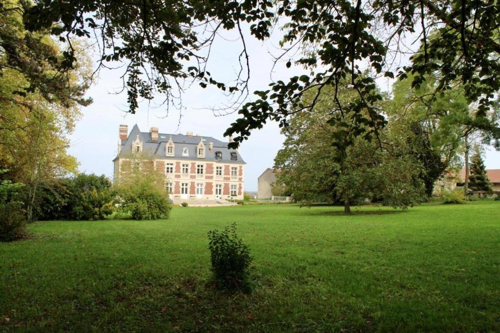 una casa grande en medio de un campo verde en Château du Mont de Guny 