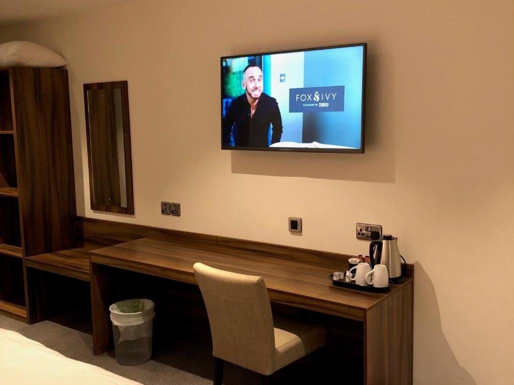 a room with a desk with a television on the wall at Rivington Lodge in Bolton