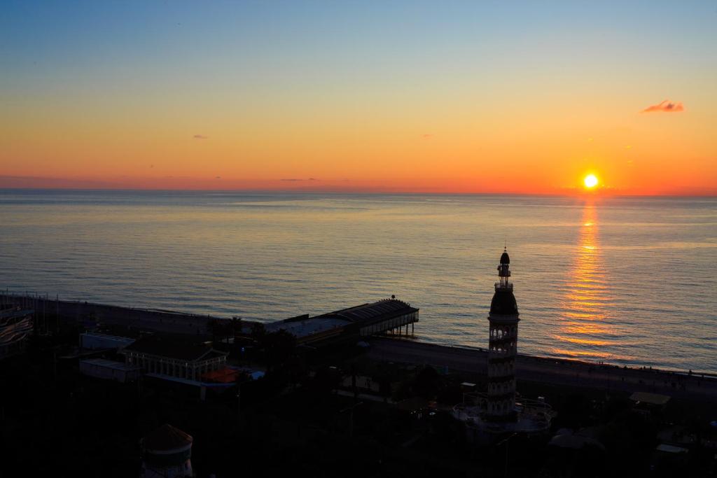 a sunset over the ocean with a clock tower at Orbi City on the Beach in Batumi