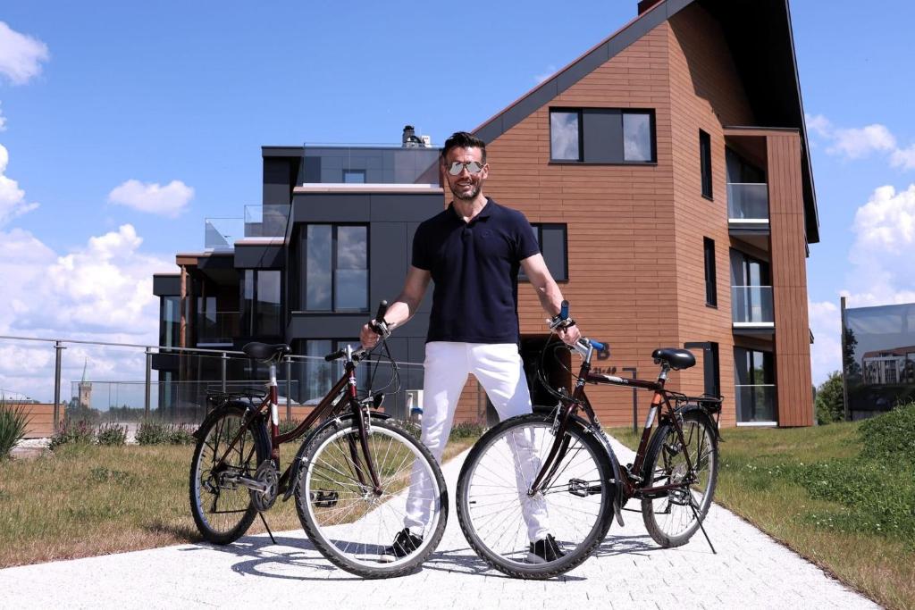 Un homme se tient à côté de deux vélos dans l'établissement Pratum Pink&Blue Mikołajki Apartament de lux z kominkiem, prywatnym pomostem i 400m strefą wellness, à Mikołajki