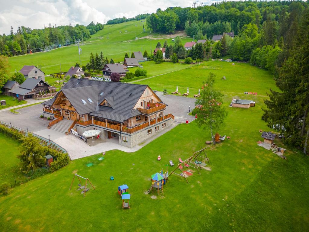 an aerial view of a large house on a green field at Olza Karczma i pokoje in Istebna