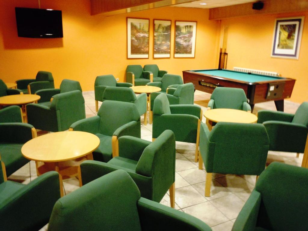 a room with green chairs and a pool table at Hotel Urogallo in Vielha