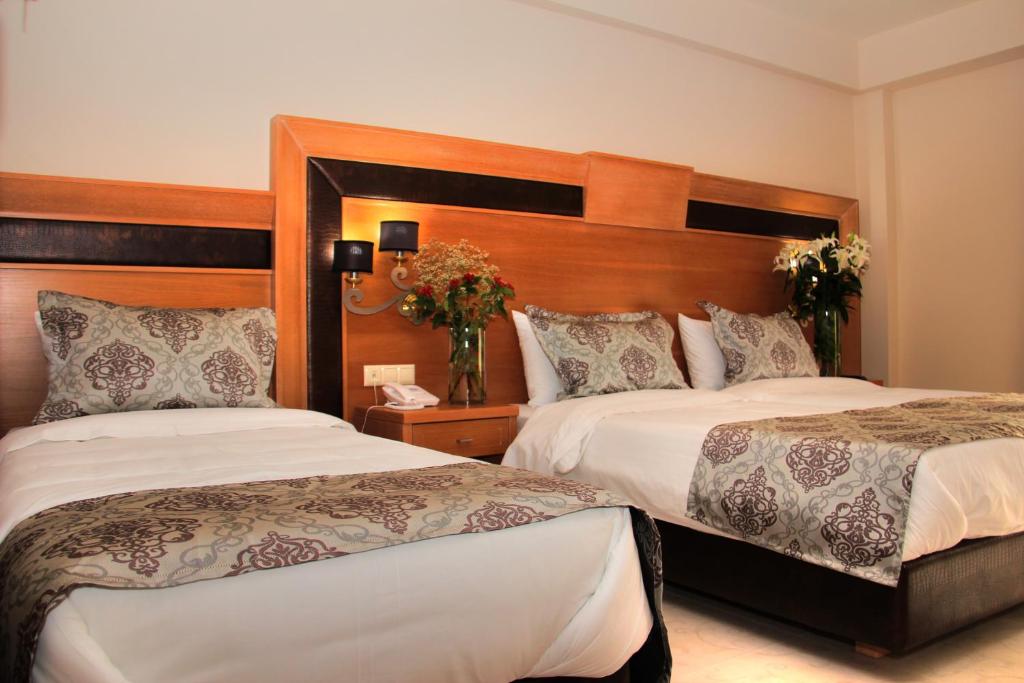 a hotel room with two beds and flowers in a room at Grand Meteora Hotel in Kalabaka