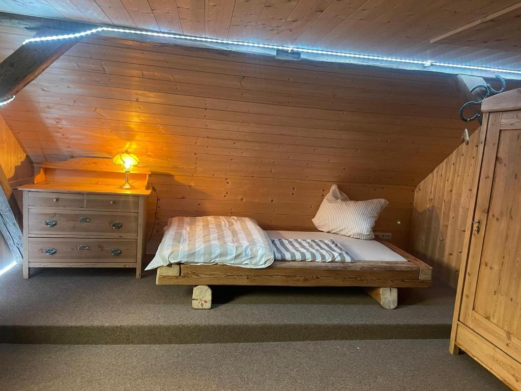 małe łóżko w drewnianym pokoju z komodą w obiekcie Ferienhaus Linde w mieście Warmensteinach