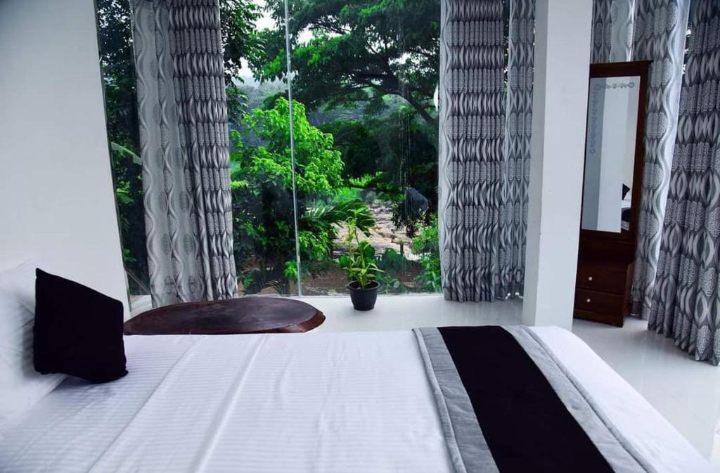 a bedroom with a bed and a large window at Nice Place Kandy in Kandy