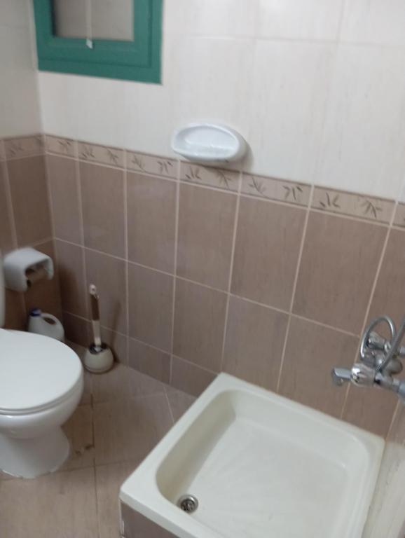 a bathroom with a white toilet and a sink at All in One in Sharjah