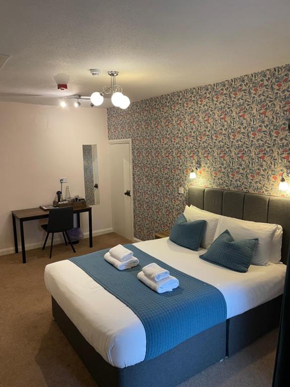 een slaapkamer met een groot bed en handdoeken bij The Wheatsheaf Inn in Ingleton 