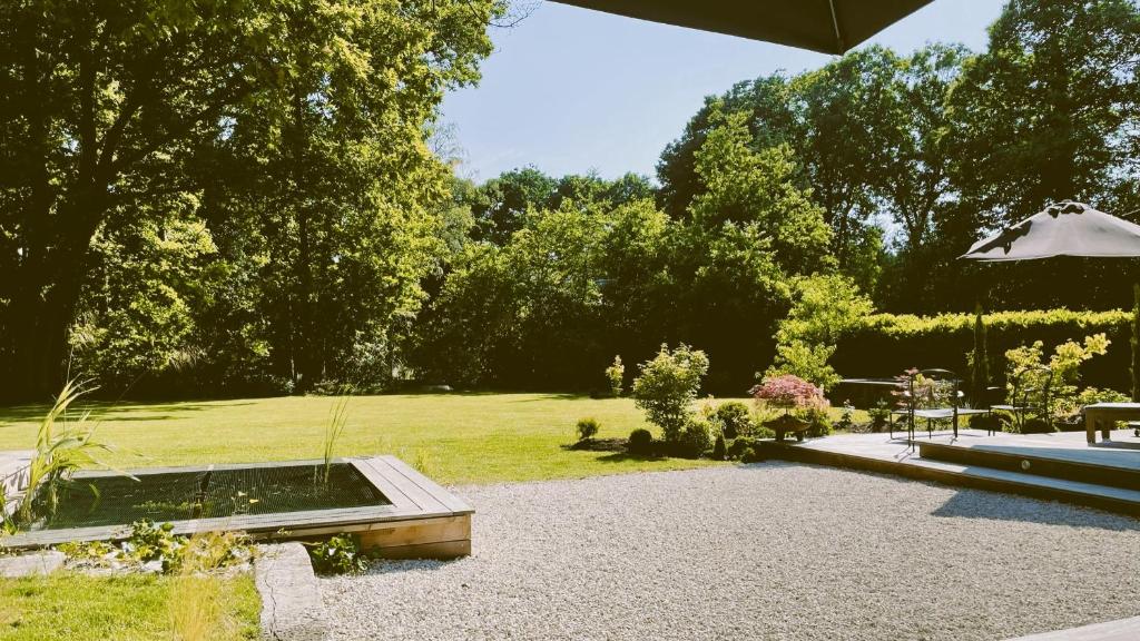 einen Garten mit einem Teich und einem Sonnenschirm in der Unterkunft Bourgogne en Grez in Grez-Doiceau