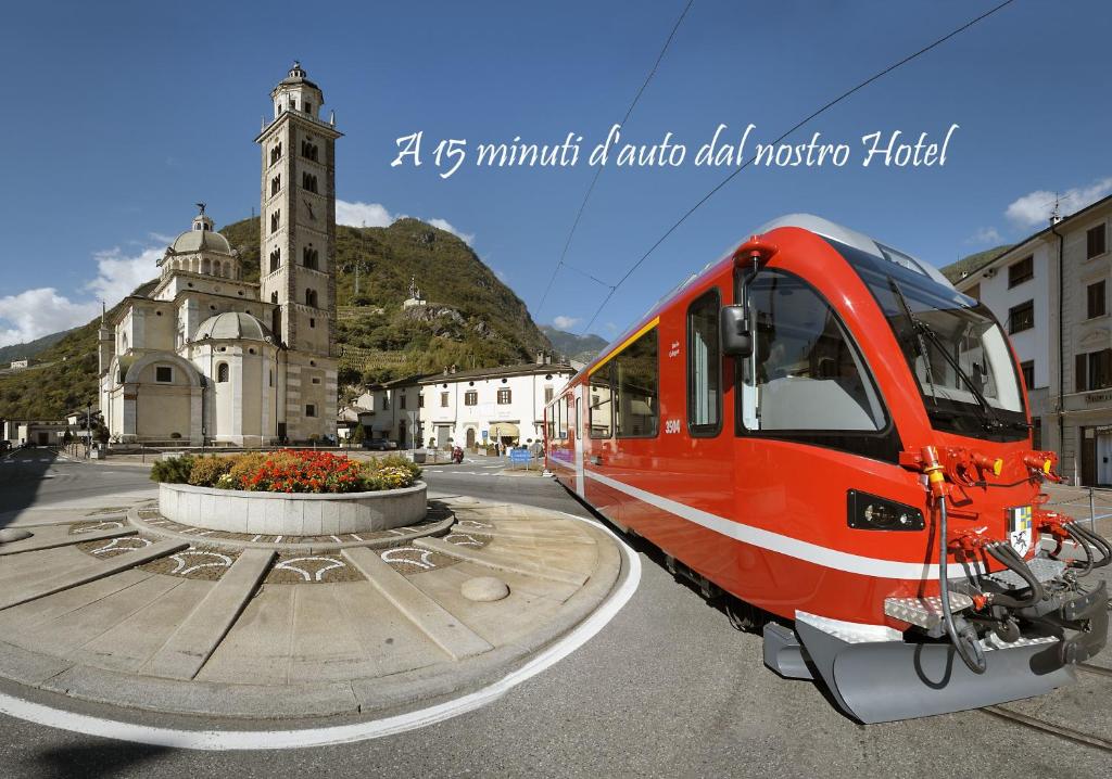 a red train is parked in front of a building at Hotel La Rosa in Teglio