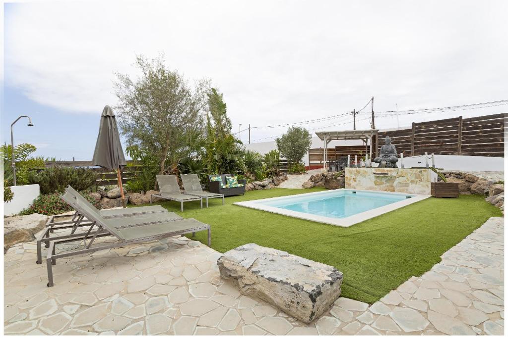 un cortile con piscina, panchina e roccia di 7 Moons Resort B Only Adults a San Bartolomé