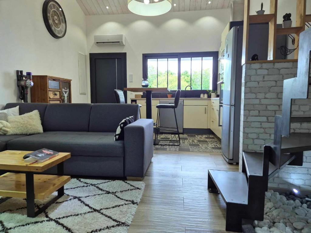 a living room with a blue couch and a kitchen at Maisonnette cosy proche de La Rochelle et de L'Ile de Ré in Saint-Xandre