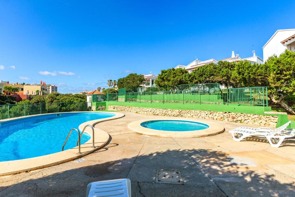 a swimming pool with two chairs and a table at Biniforcat in Cala en Forcat