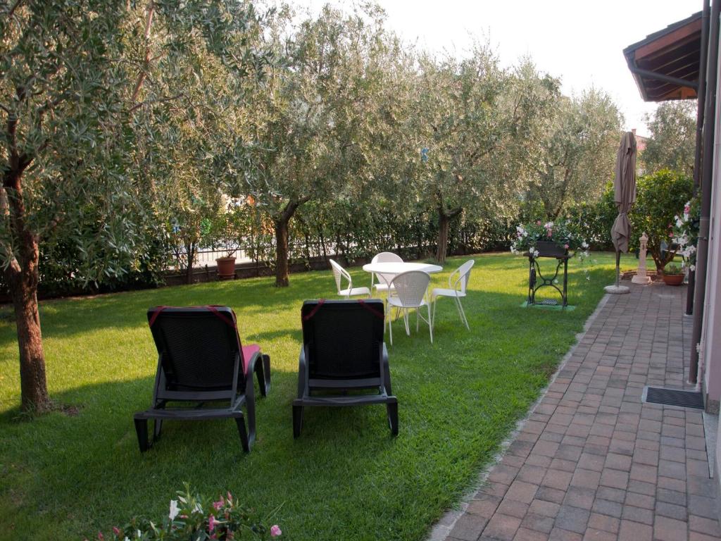 un grupo de sillas y una mesa en el césped en Appartamenti Villa Adriana Torbole, en Nago-Torbole