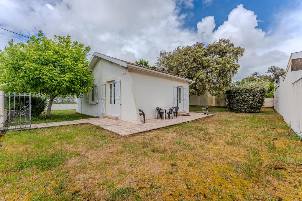 une petite maison blanche avec une table et des chaises dans une cour dans l'établissement Villa Bikini, à Soulac-sur-Mer