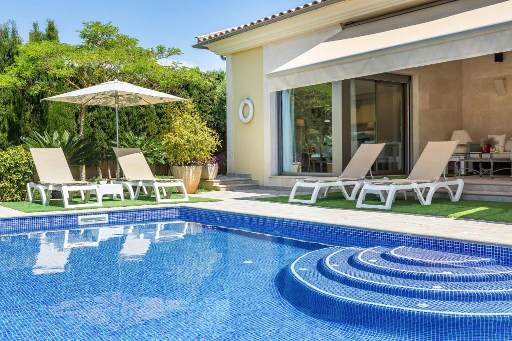 uma piscina com cadeiras e um guarda-sol ao lado de uma casa em Bellviure Luxury Villa em Marratxí 