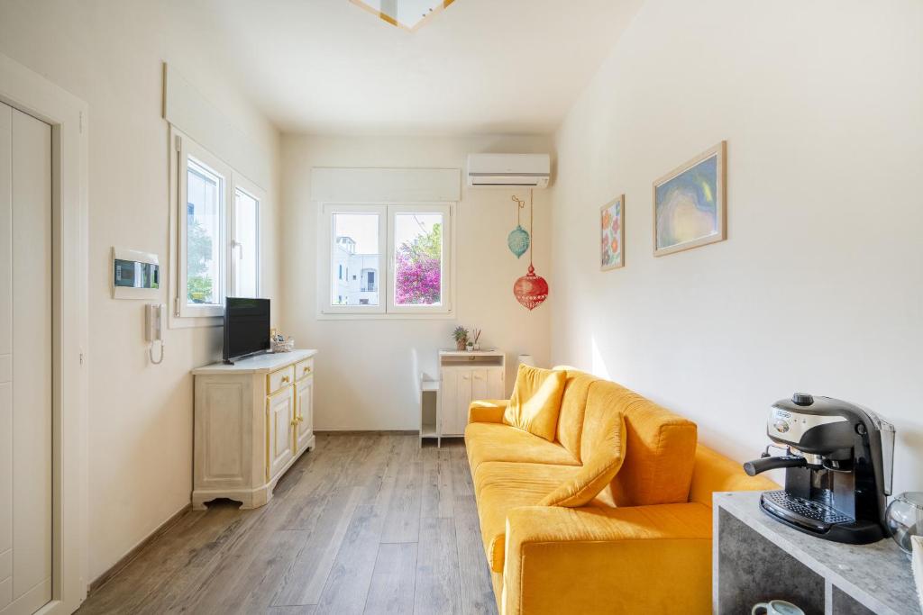 sala de estar con sofá amarillo y TV en Gufo di Mare - Giallo, en Savelletri di Fasano