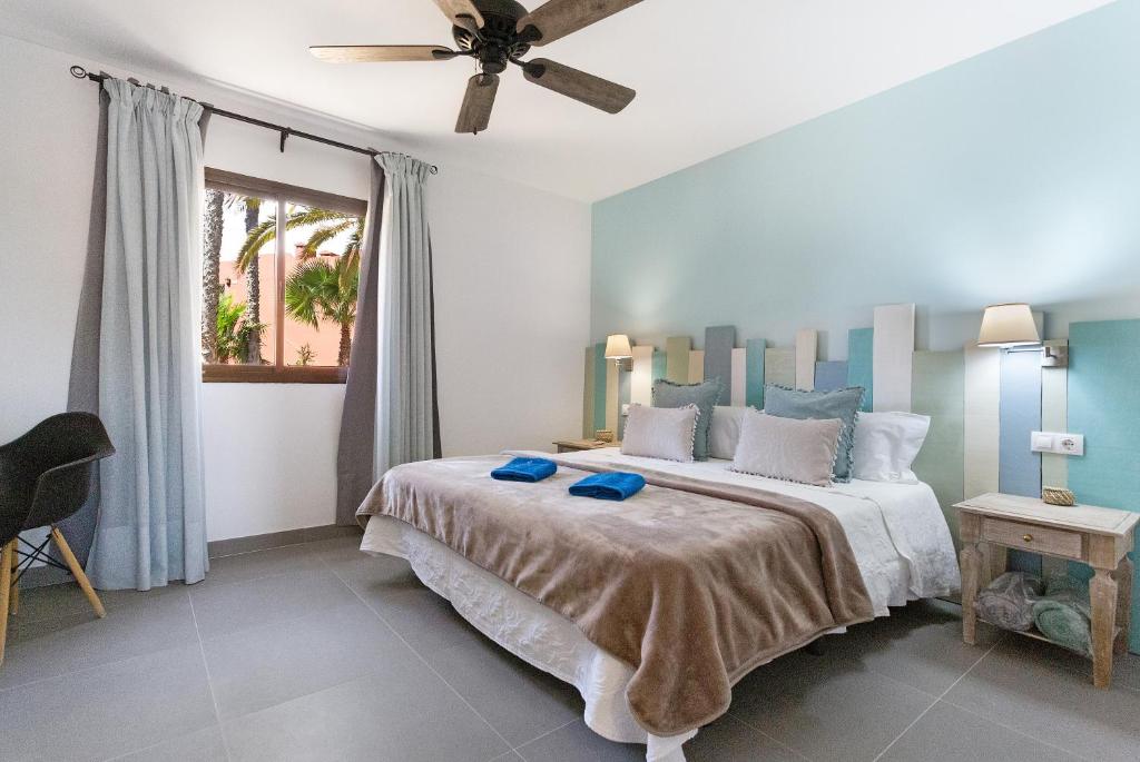 een slaapkamer met een groot bed met een plafondventilator bij Casa Desierto Azul in Corralejo