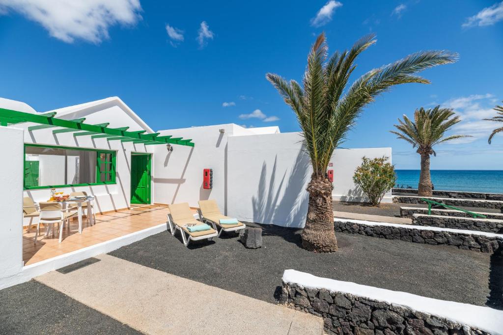 une maison sur la plage avec des palmiers et l'océan dans l'établissement Bungalow Alma Ocean View, à Puerto del Carmen
