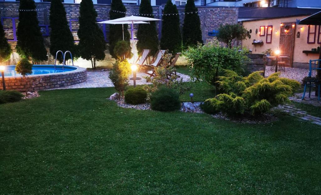 a backyard at night with a pool and landscaping at Guest House Relić in Sombor