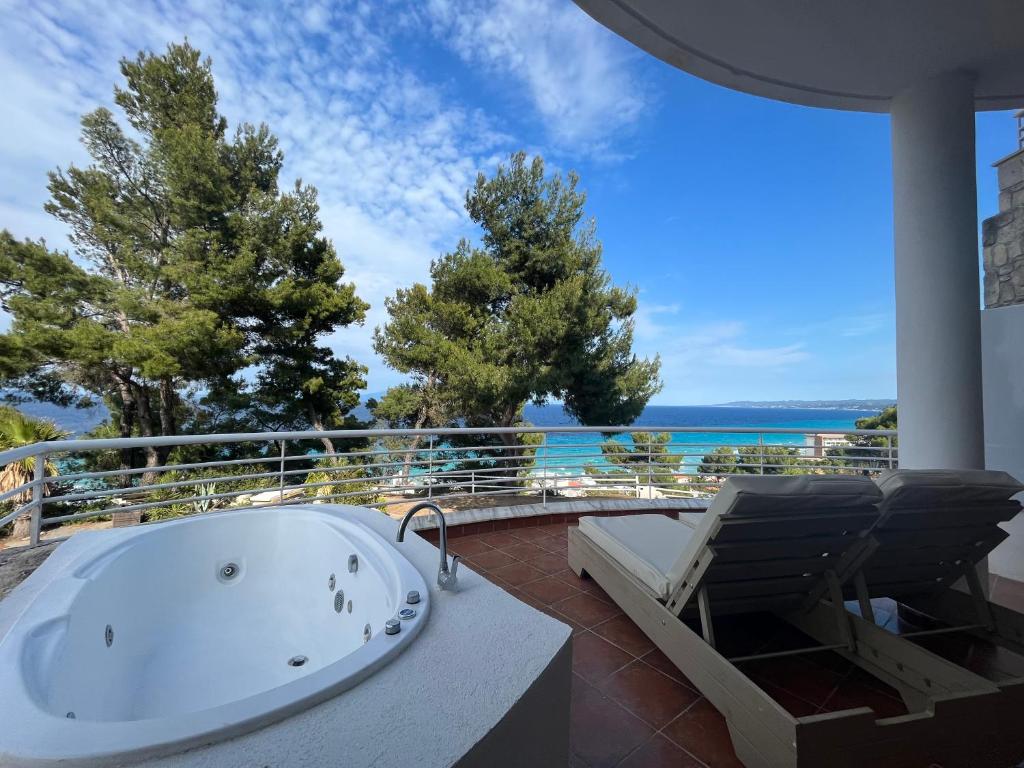 a bath tub on a balcony with a view of the ocean at Amelia Apartments in Kallithea Halkidikis