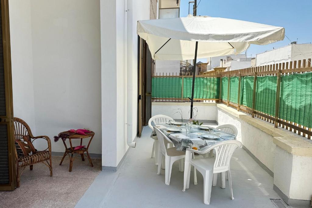 a white table and chairs with an umbrella on a balcony at Vento Di Mare in Torre Lapillo