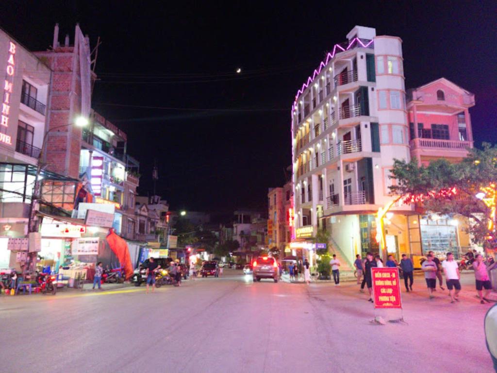una calle concurrida de noche con gente y coches en Thái Thịnh Hotel, en Dồng Văn