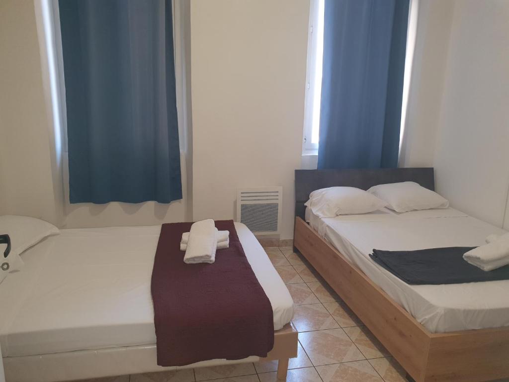 twee bedden in een slaapkamer met blauwe gordijnen bij Hotel Du Centre in Marseille
