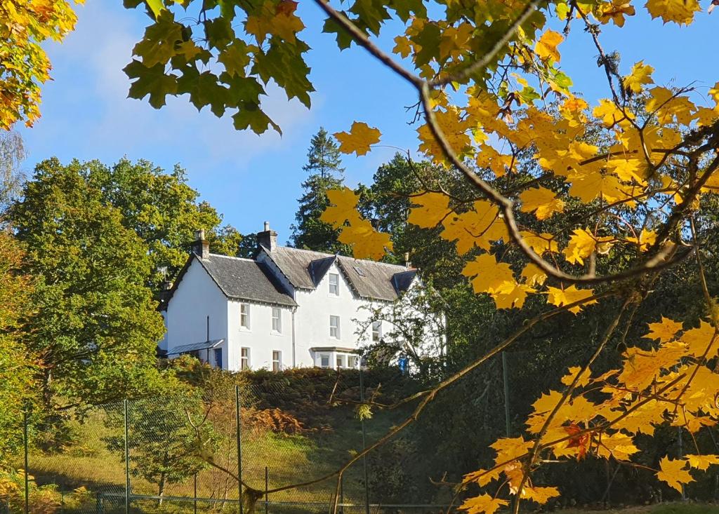 una casa blanca en una colina con hojas de otoño en Tirindrish House B&B, en Spean Bridge