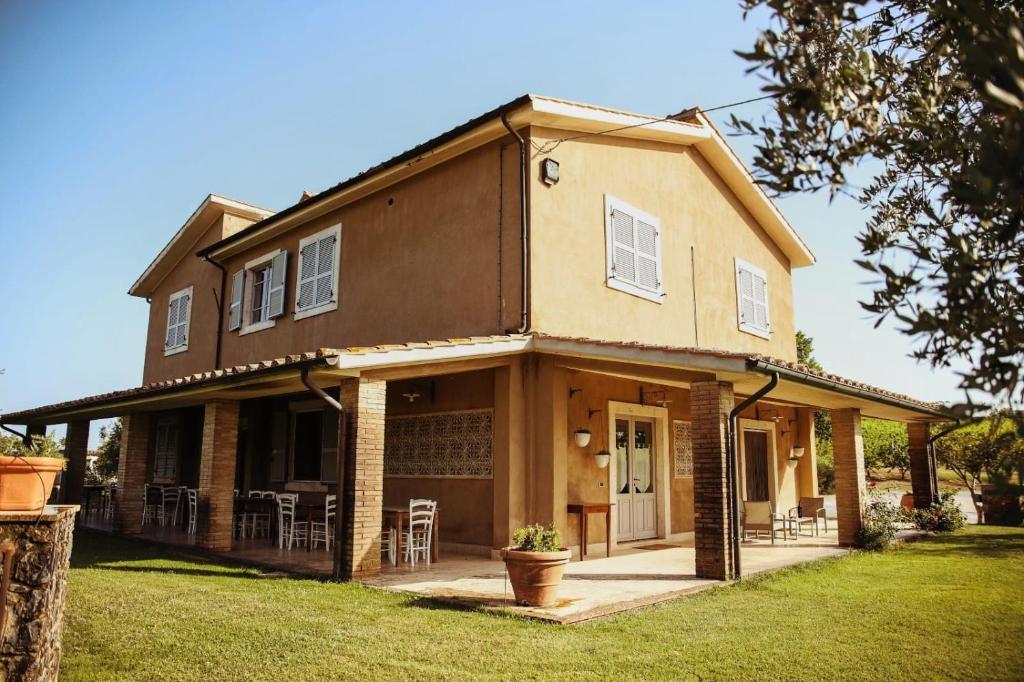 uma casa grande com um alpendre e um relvado em Bio Agriturismo Poggio Aione em Saturnia