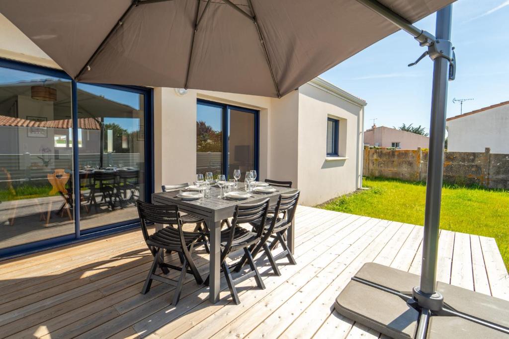 - une table avec des chaises et un parasol sur une terrasse dans l'établissement Maison Familiale avec jardin proche de la mer Parking, à Les Sables-dʼOlonne