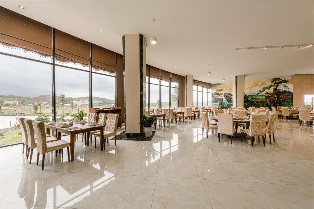 een eetkamer met tafels en stoelen en grote ramen bij Muong Thanh Grand Ha Tinh Hotel in Kỳ Anh