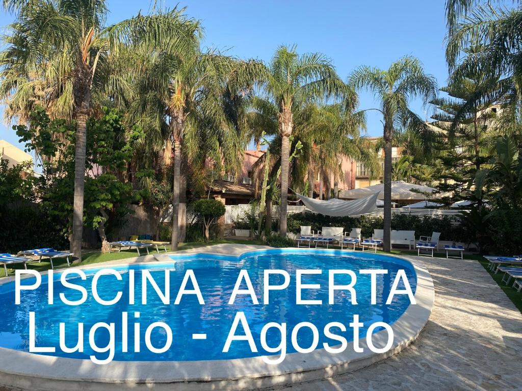 a sign in front of a swimming pool with palm trees at Casantica B&B Turismo Rurale in Milazzo