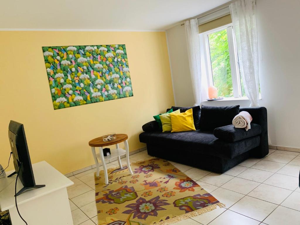 ein Wohnzimmer mit einem schwarzen Sofa und einem Fenster in der Unterkunft Casa Cinzia Sara in Eckernförde