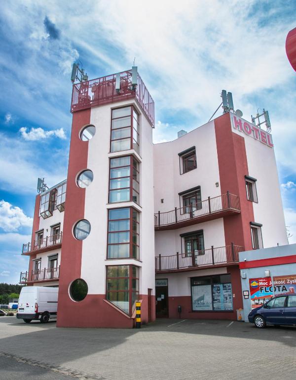 a tall red and white building with a balcony at Perła in Leszno