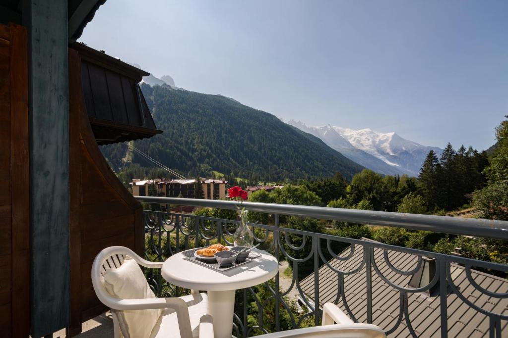 a table and chairs on a balcony with a view of a mountain at Résidence Le Cristal-Mont Blanc 18 - Happy Rentals in Argentiere