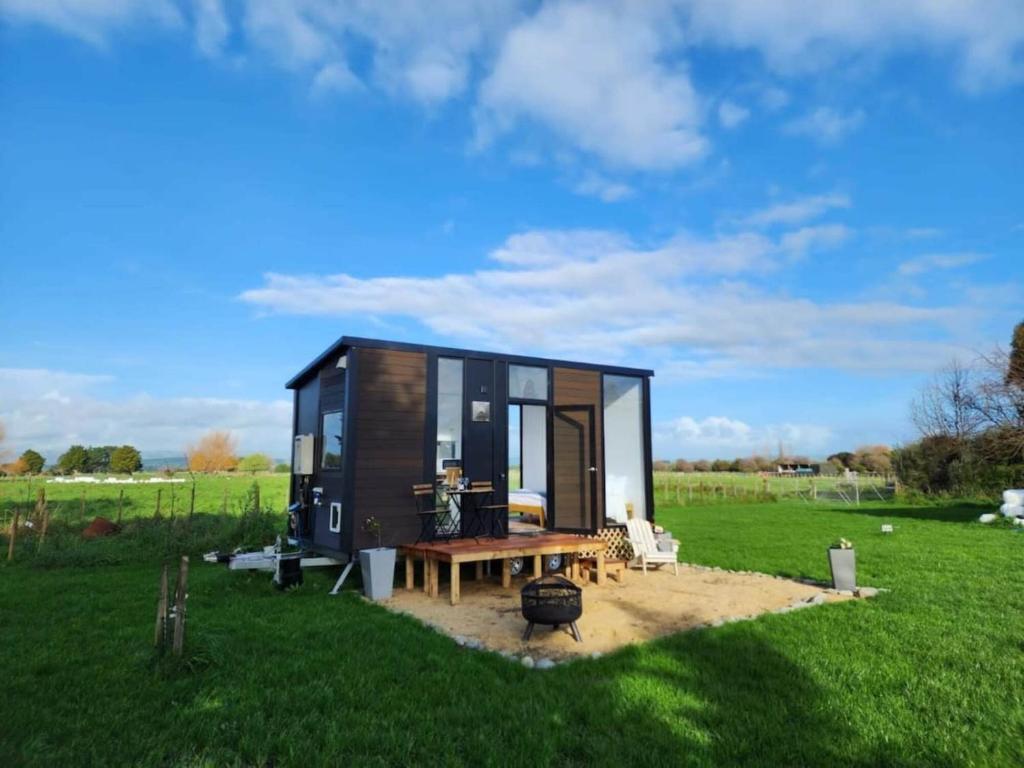 ein kleines schwarzes winziges Haus auf einem Feld in der Unterkunft Taratahi Escape in Clareville