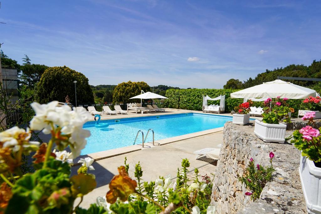een zwembad met stoelen, parasols en bloemen bij Villa Pesce in Selva di Fasano