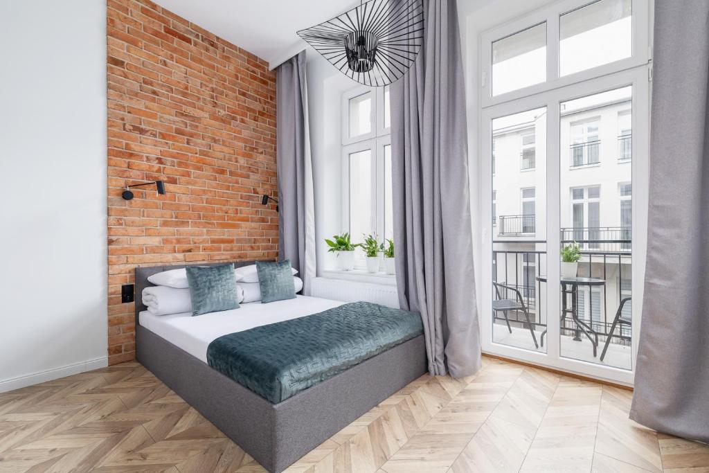 a bedroom with a bed and a brick wall at Apartment with Balcony - Starowiślna 41 in Kraków