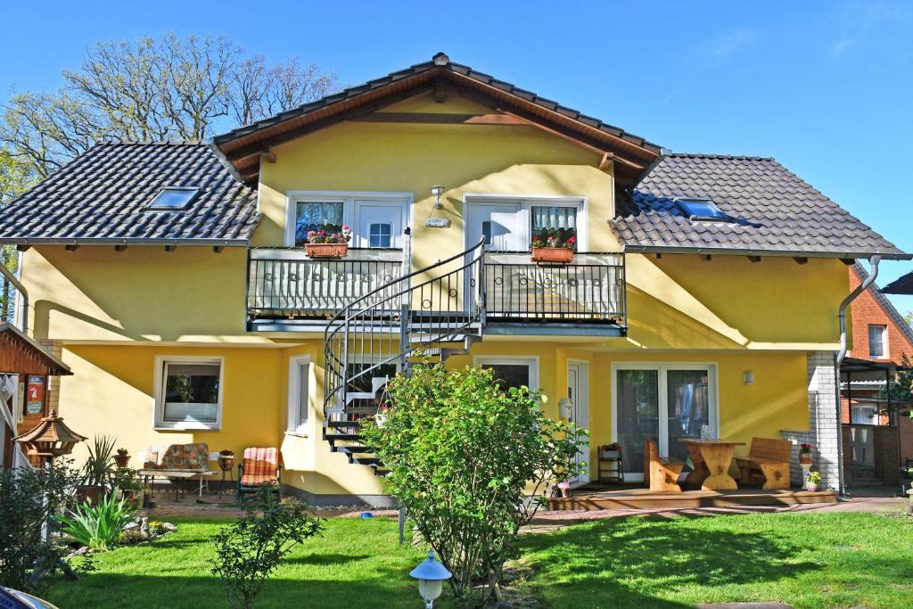una casa gialla con balconi e un cortile di Ferienwohnungen Familie Dinda a Baabe