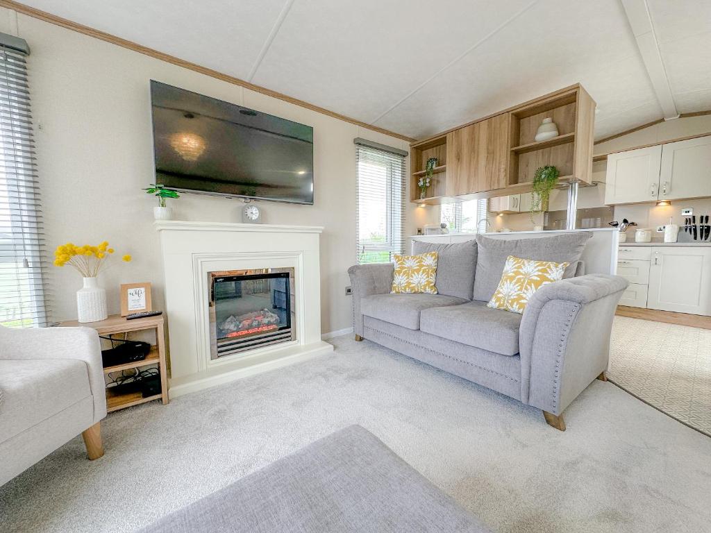 a living room with a couch and a fireplace at Serena Holiday Caravan in Bassenthwaite