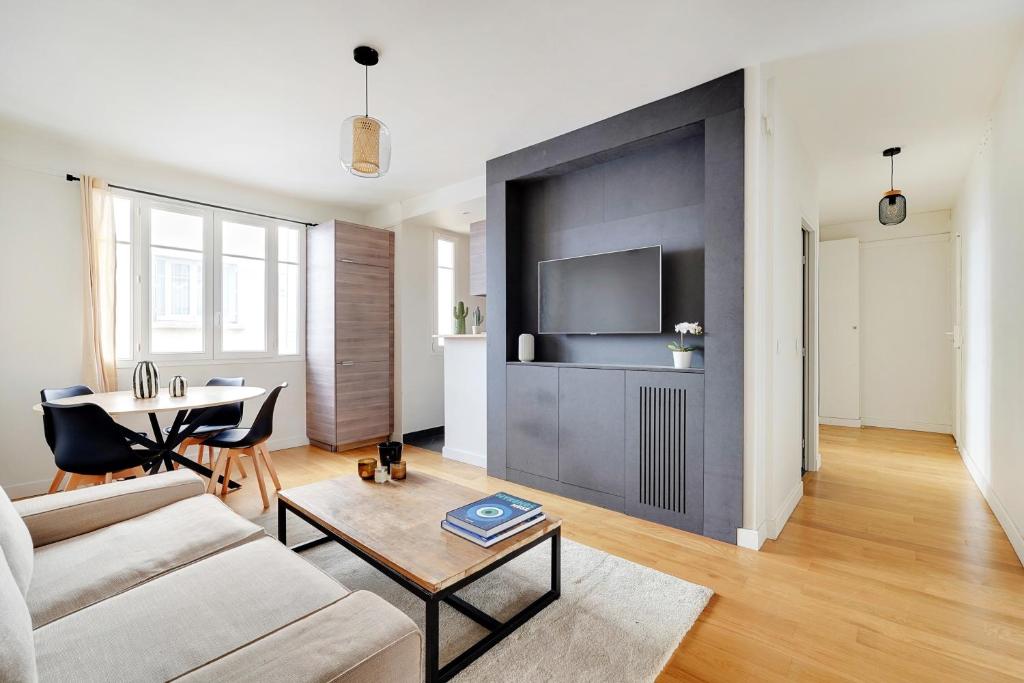 un salon avec un canapé et une télévision sur un mur dans l'établissement T3 Boulogne - Roland Garros/Parc des Princes, à Boulogne-Billancourt