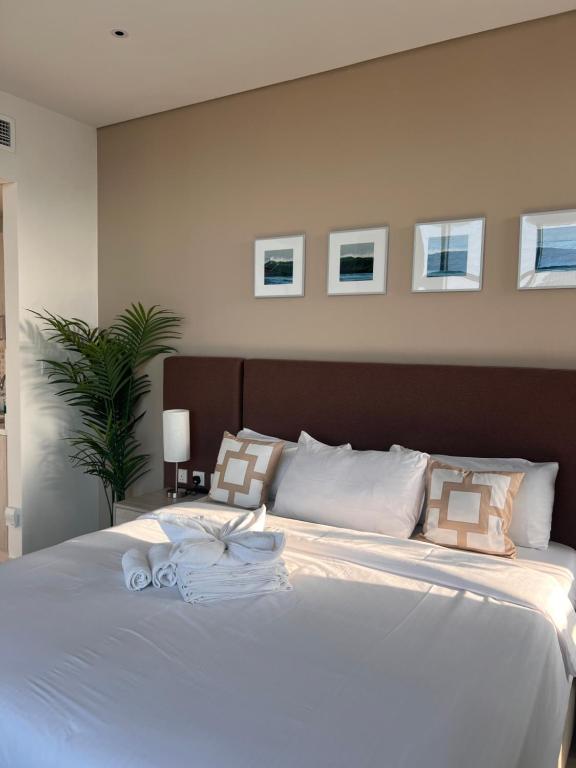 ein Schlafzimmer mit einem großen weißen Bett mit Bildern an der Wand in der Unterkunft Serenity Suites studio in Seven Palm corner view in Dubai