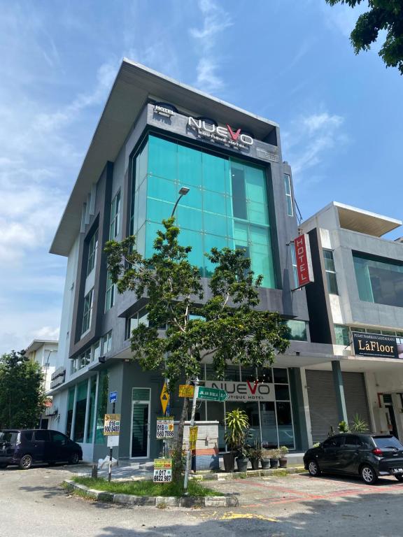 een groot glazen gebouw met een boom ervoor bij Swing & Pillows - NueVo Boutique Hotel Kota Kemuning in Shah Alam