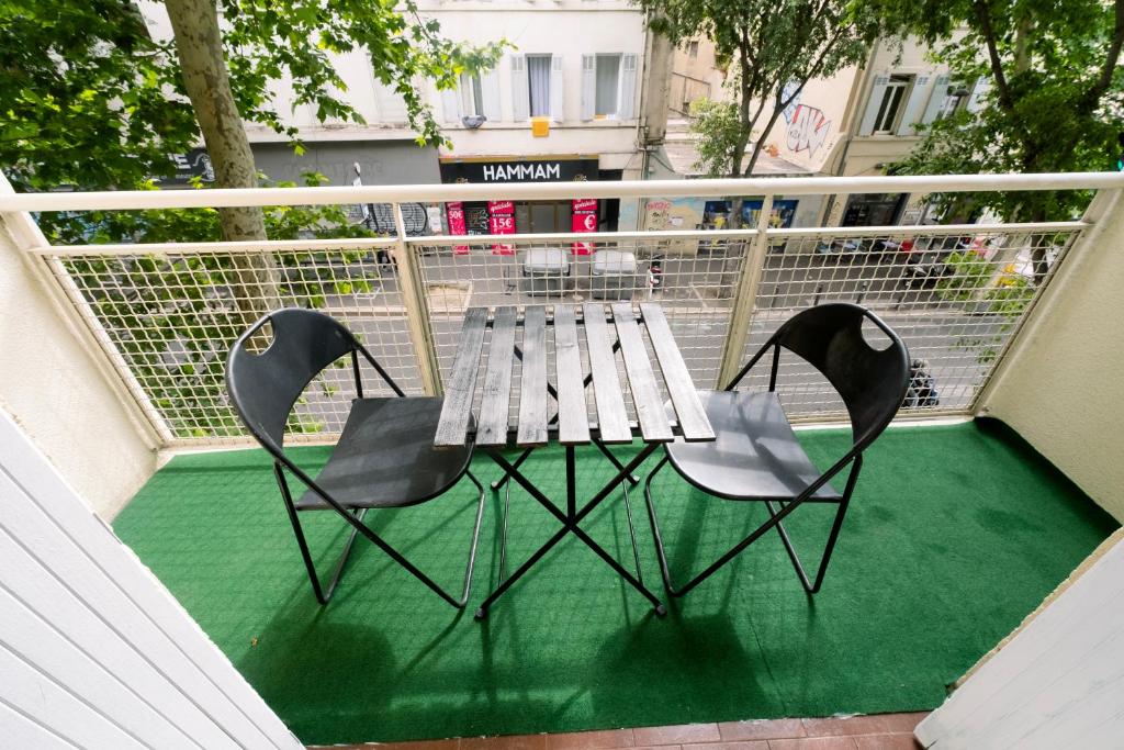 une table de pique-nique et deux chaises sur un balcon dans l'établissement Jolie appartement à 10 minutes de la gare de Marseille, à Marseille