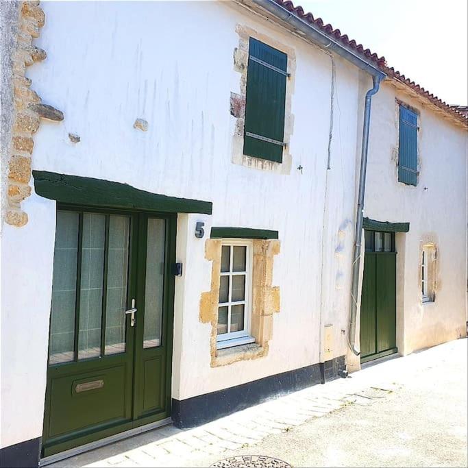 - un bâtiment blanc avec des portes et des fenêtres vertes dans l'établissement Chai restauré au cœur du village, à Ars-en-Ré
