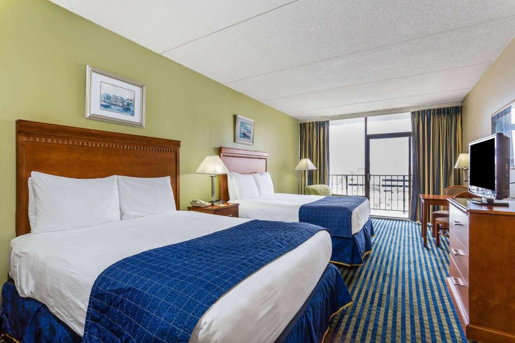 a hotel room with two beds and a television at Days Inn by Wyndham Virginia Beach At The Beach in Virginia Beach