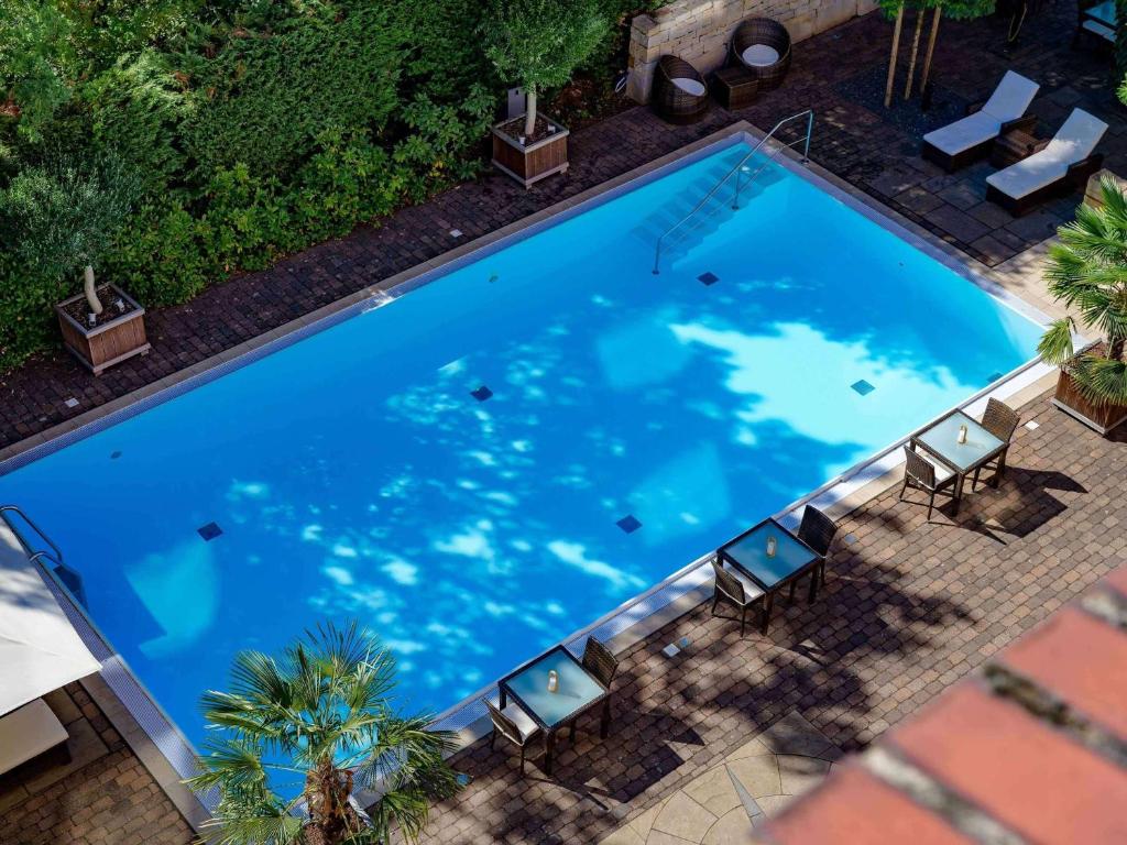 an overhead view of a large blue swimming pool with chairs at Mercure Hotel Hannover Medical Park in Hannover