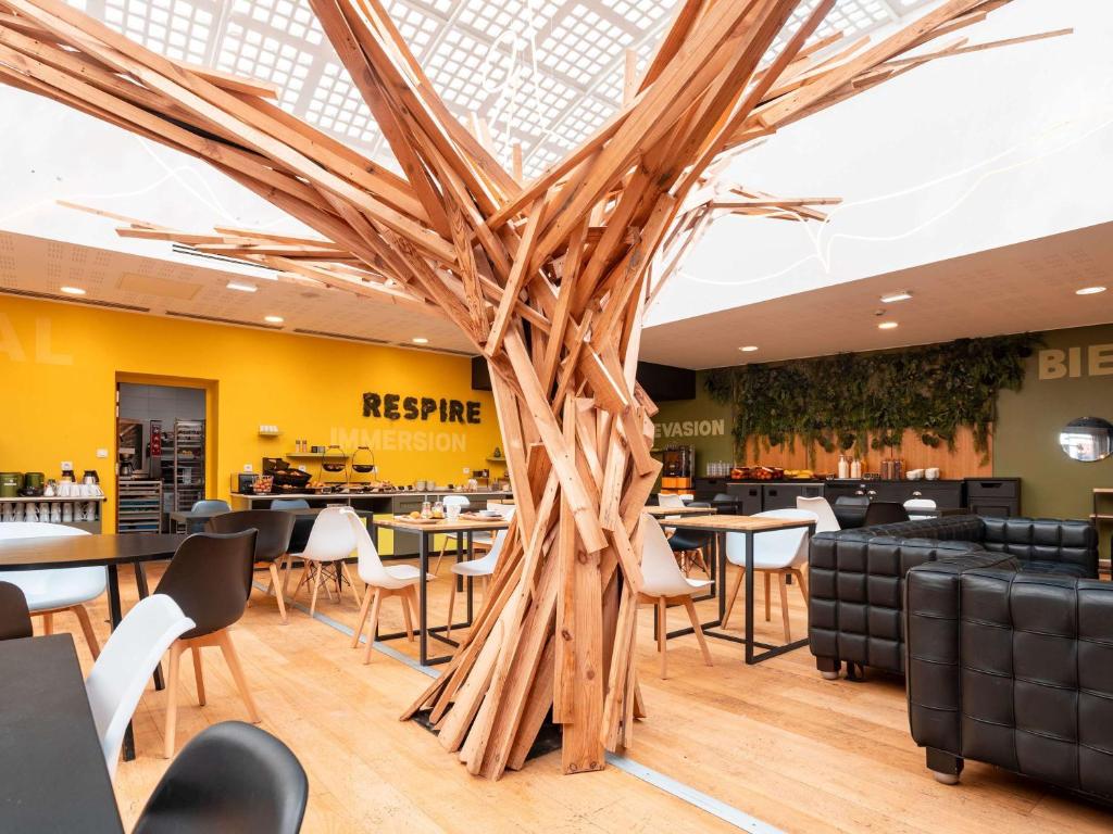 een grote houten boom in een restaurant met tafels en stoelen bij ibis Styles Calais Centre in Calais